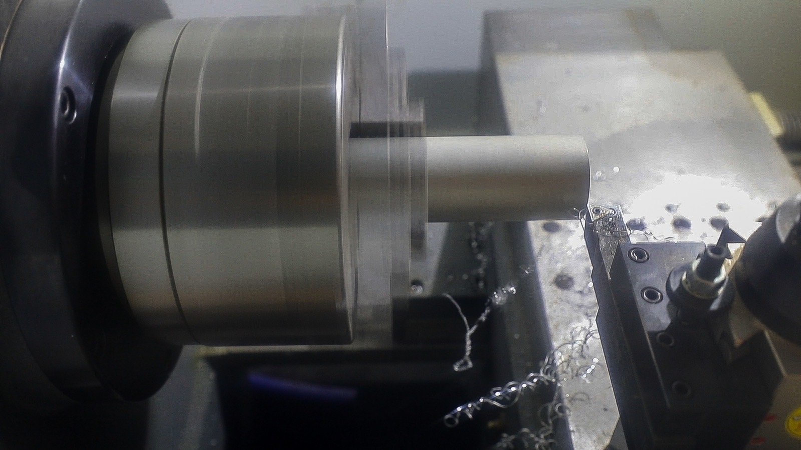 A CNC lathe turning a metal part under coolant spray