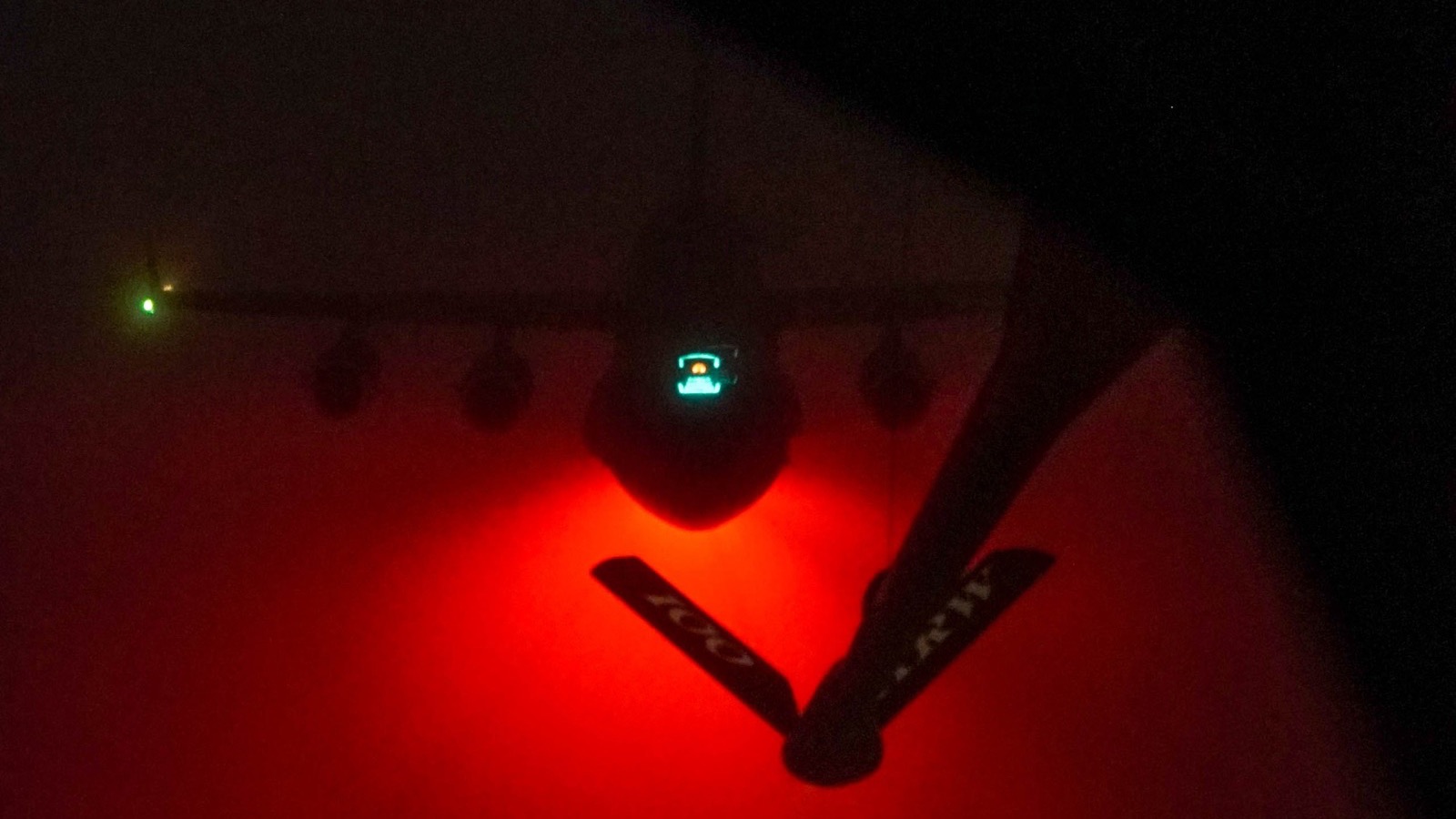 The underside of a cargo aircraft lit red during night aerial refueling